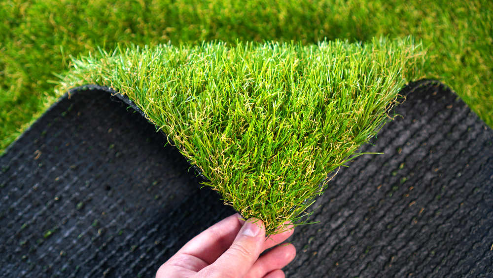 Hand,holding,an,artificial,grass,roll.,greenering,with,an,artificial